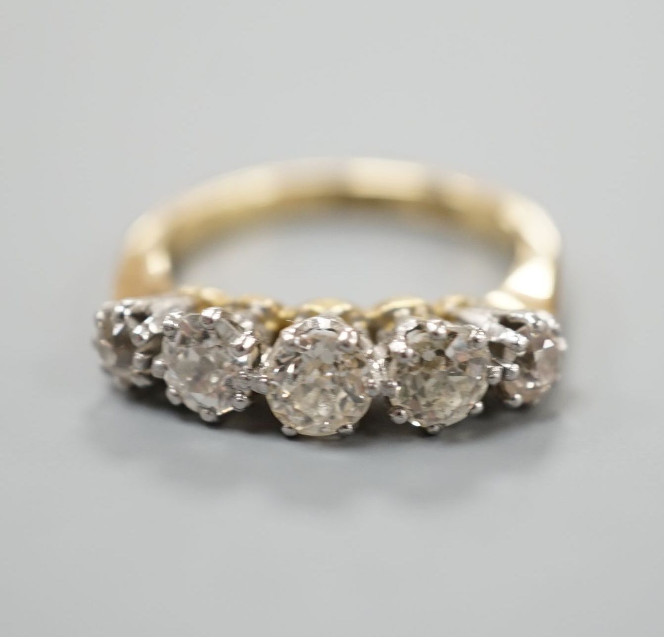 An 18ct and graduated five stone diamond set half hoop ring, size K, gross weight 4 grams.